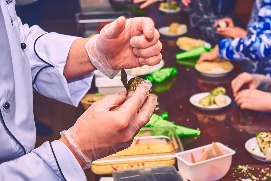 Chef demonstrating hands-on food preparation in a cooking class setting