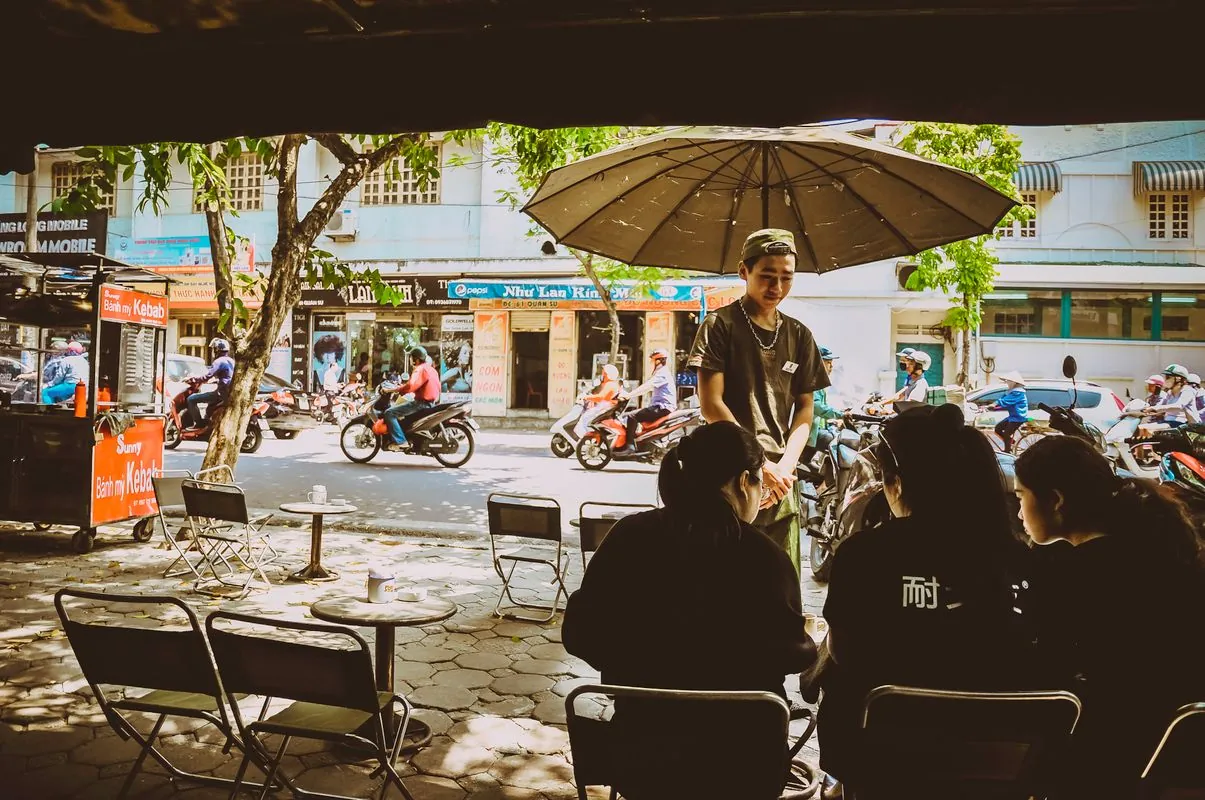 Outdoor street cafe in Hanoi with people dining, typical stop on a Hanoi food tour