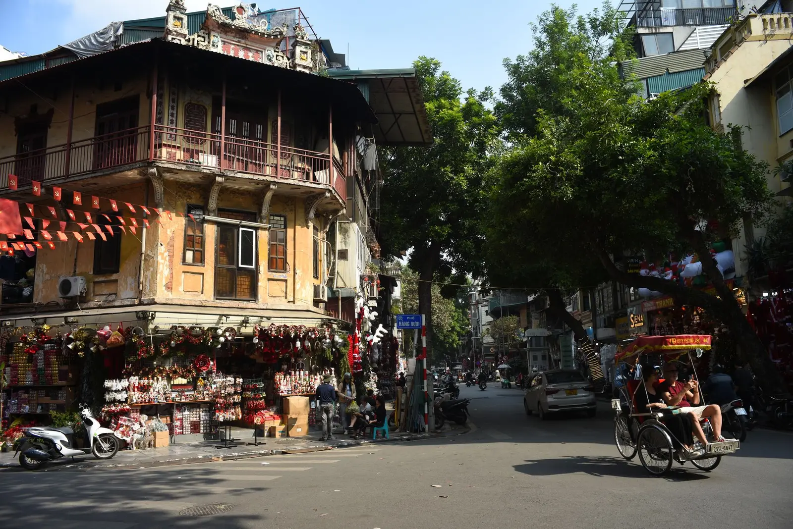 Bustling Hanoi Old Quarter street scene with a rickshaw and traditional shophouses